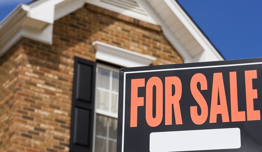 Home for sale - a sign in front of a brick house